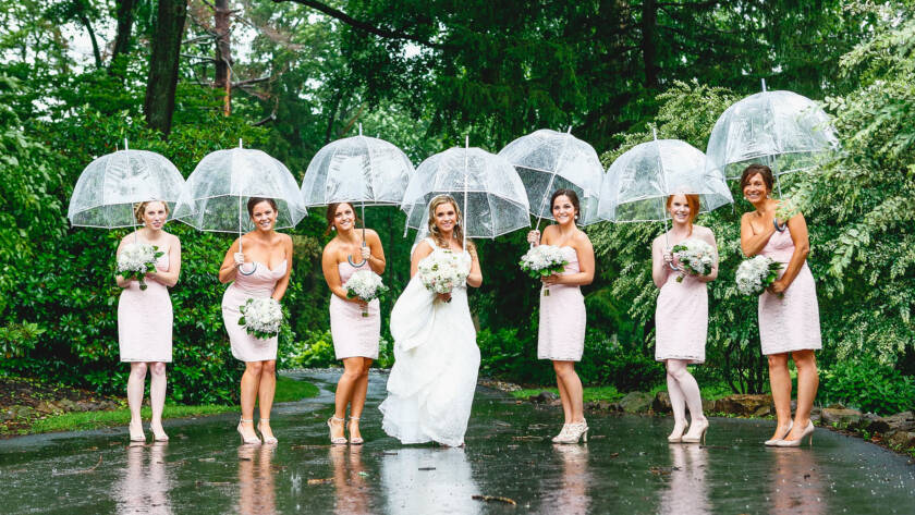 Bride and bridesmaids holding umbrellas in the rain