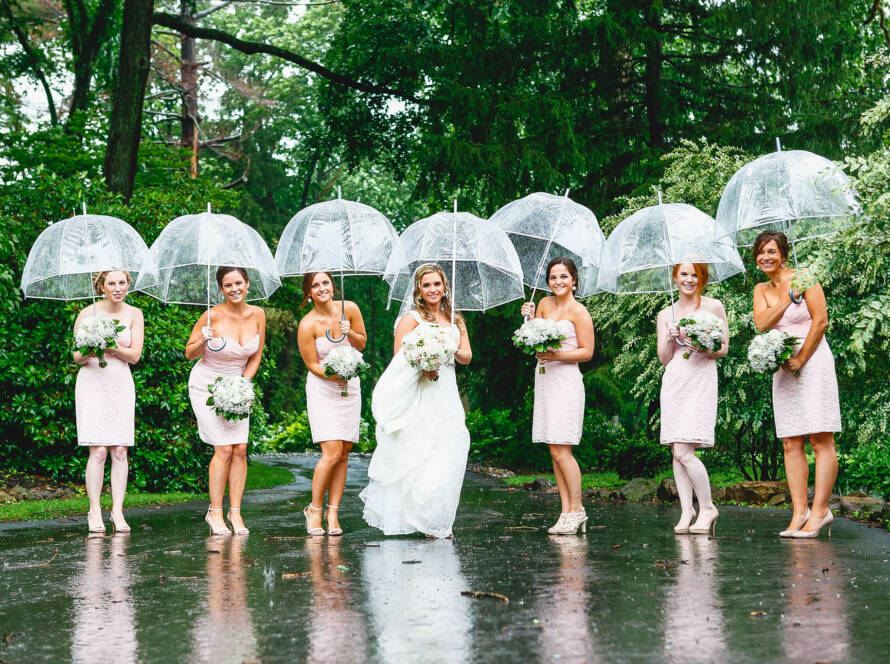 Bride and bridesmaids holding umbrellas in the rain