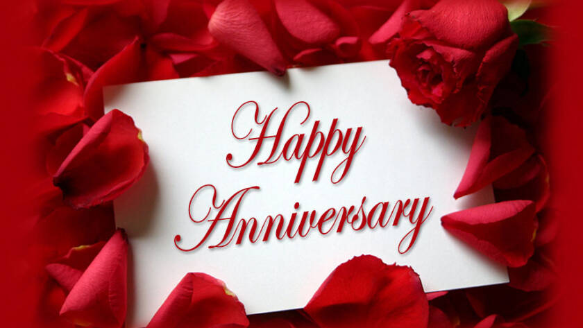 Happy Anniversary written on white card and surrounded by red flower petals for anniversary parties