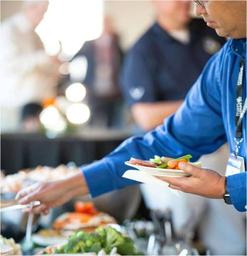 man in blue shirt selecting food from a buffet at a corporate event